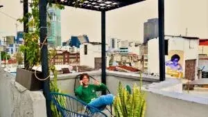 Corner on the terrace; hostel guest taking on the phone, relaxing in a lounge (Acapulco) chair; surrounded by a couple of plants; view from the terrace behind.